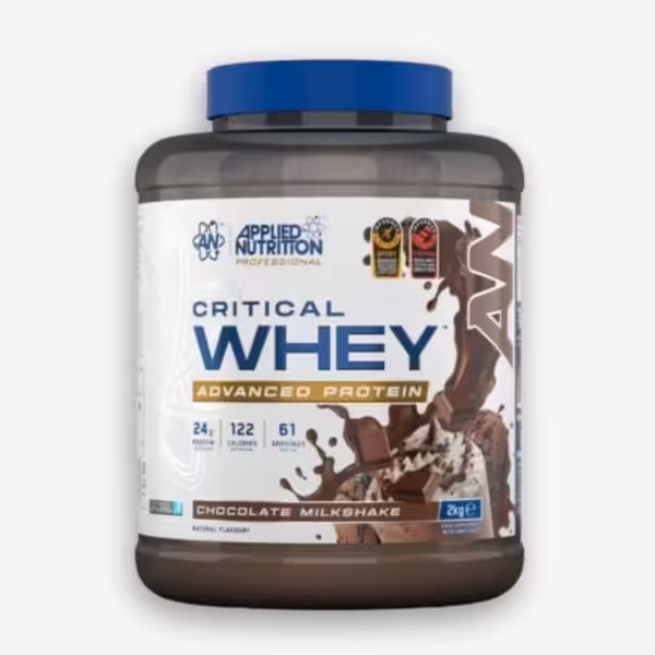 The image displays a large dark gray tub of Applied Nutrition Critical Whey Advanced Protein powder with a blue lid, featuring a label that depicts a chocolate milkshake with splashing liquid and chocolate chunks.