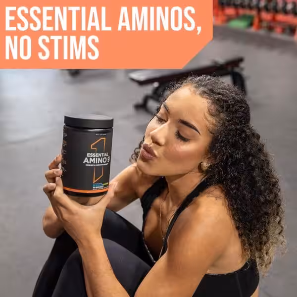 Woman sitting in a gym holding a tub of Rule One Essential Amino 9 supplement. Text reads: Essential Aminos, No Stims